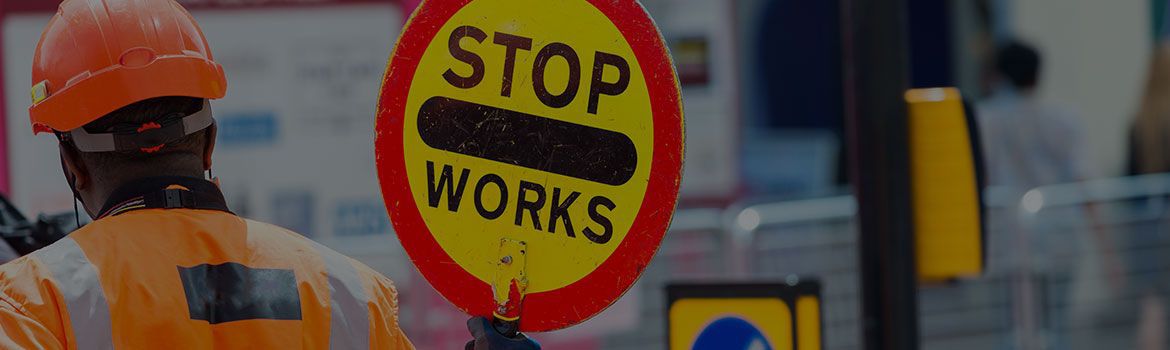 Health & Safety: A worker in a high-vis jacket holding up a 'stop works' sign.